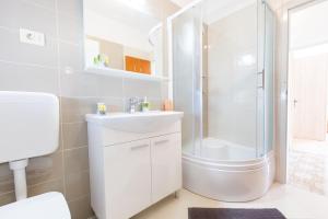 baño blanco con ducha y lavamanos en SAN Apartments, en Slatine