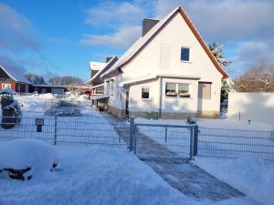 a white house with a fence in the snow at Ferienhaus Wiesenblick in Hüttenrode +19 photos