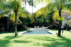 a hammock in the middle of a yard with palm trees at Villa Fleur in Tumbak Bayuh