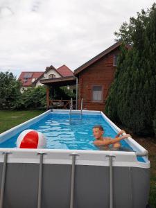 a young boy in a swimming pool with a ball at Orla Chata Domy in Świnoujście