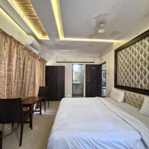 a bedroom with a bed and a table and a desk at New White House Hotel in Pune