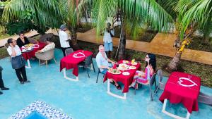 a group of people sitting at tables with food on them at Malika Blue Hotel Nungwi, Zanzibar in Banda Kuu