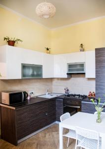 リヴィウにあるSoborna Comfort Placeの白いキャビネットと白いテーブル付きのキッチン
