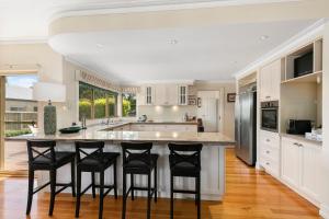 Una cocina con una gran isla con taburetes de bar. en Sea Breeze on the Crescent, en Inverloch