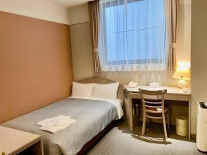 a hotel room with a bed and a desk and a window at The Hamilton Sapporo Hotel in Sapporo