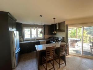 a kitchen with a island with chairs and a counter top at Spa & River - Aux Berges du Nord 3 in Prévost