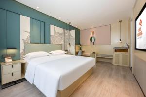 a bedroom with a large white bed and a kitchen at Jin Yi Youxuan Hotel Baotou Wanda Plaza Branch in Baotou