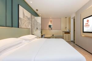 a bedroom with a large white bed and a tv at Jin Yi Youxuan Hotel Baotou Wanda Plaza Branch in Baotou