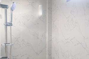 ein Bad mit einer Dusche und weißen Marmorfliesen in der Unterkunft RedDoorz at Risma Hostel ITERA Lampung in Kedaton