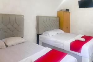 zwei Betten in einem kleinen Zimmer mit roter und weißer Bettwäsche in der Unterkunft RedDoorz at Risma Hostel ITERA Lampung in Kedaton