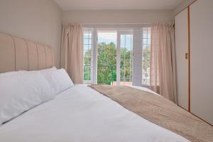 Una cama blanca en una habitación con ventana. en Seaview Haven - Luxury Coastal Escape Simon's Town, en Simonʼs Town