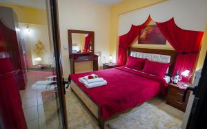een slaapkamer met een rood bed en een spiegel bij Relax pozar in Kato Loutraki