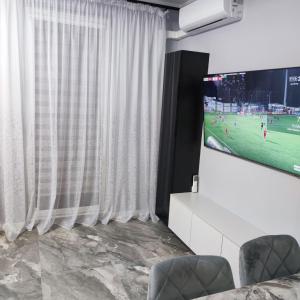 a living room with a tv and white curtains at Studio Leszczyńskiego Przemyśl in Przemyśl
