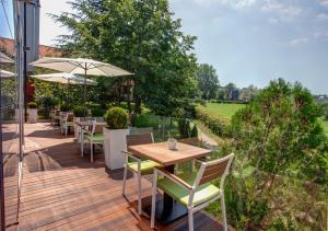 eine Holzterrasse mit Tischen, Stühlen und einem Sonnenschirm in der Unterkunft Hotel Heritage in Belgrad