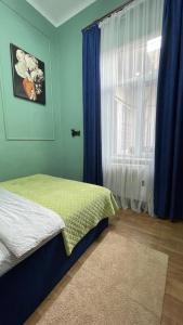 a bedroom with a bed and a window with blue curtains at Двокімнатна квартира з кондиціонером в історичному центрі міста in Chernivtsi