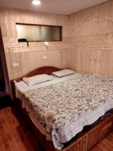 a bed in a room with a wooden wall at Hotel Palestine in Pahalgām
