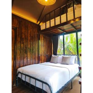 Ban Tha MaphraoにあるCheewatra Farmstay Coconut Houseのベッドルーム1室(白いシーツと木製のベッド1台付)