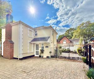 ein weißes Haus mit einem Tor und einem Zaun in der Unterkunft Gateman's Cottage - Three Bedroom Detached Home - Free Parking - Close to New Forest and Beaches in West Moors