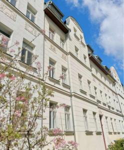 a large white building with windows and a tree at WG Zimmer im Leipziger Westen in Leipzig