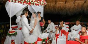 a bride and groom are standing under a white tent at Hotel Boutique El Mirador in Arboletes +42 photos