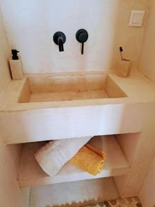 a bathroom with a sink with towels on a shelf at Villa Face a l'océan in Rufisque +19 photos