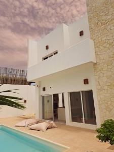a white house with a swimming pool in front of it at Villa Face a l'océan in Rufisque