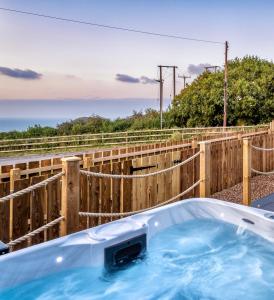 a jacuzzi tub with a wooden fence at North Devon Resort One bedroom sea view hot tub Residence in Ilfracombe