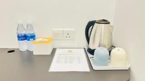 a counter with a coffee maker and bottles of water at Moon Hotel in Mentekab