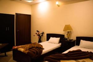 a bedroom with two beds and a vase of flowers at Kohinoor Hotel in Dargai +3 photos