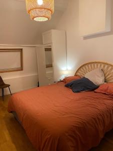 ein Schlafzimmer mit einem Bett mit einer orangefarbenen Bettdecke in der Unterkunft La charmante petite maison in Croix