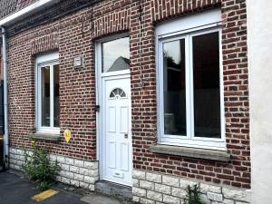 a brick building with a white door and windows at La charmante petite maison in Croix