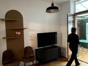 eine Person, die durch ein Wohnzimmer mit einem TV geht in der Unterkunft La charmante petite maison in Croix
