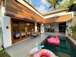 une piscine avec deux flamants roses gonflables dans une maison dans l'établissement Villa Lestari by MentariPro Bali, à Lovina 10 autres photos