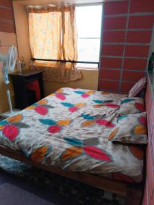 マイソールにあるGarden Room for a Coupleのベッドルーム1室(カラフルな掛け布団付きのベッド1台付)