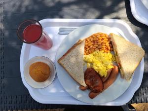 a white plate of breakfast food with eggs sausage beans and toast at Serene Cottage in Francistown