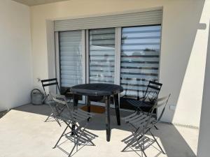 a black table and chairs on a balcony with a window at Appartement neuf in Linxe +1 photo