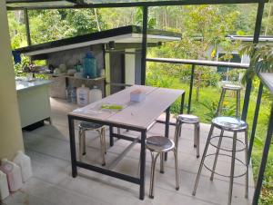 a table and stools on a patio with a kitchen at บ้านเล็กในป่าใหญ่ พัทลุง in Ban Nai Mon