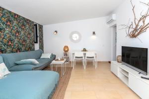 Una sala de estar con un sofá azul y un televisor. en Sa Perdiu 14 Menorca, en Cala Santandria