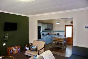 a living room with a kitchen with green walls at De Trout Huis Guesthouse in Dullstroom