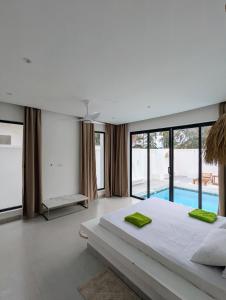 a bedroom with a large bed and a swimming pool at Amour Beach Villas in Paje