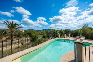 a pool with a fence and trees and a blue sky at Finca Es Galliner in Es Carritxo