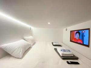 a white room with a bed and a flat screen tv at Hotel Shakti Capsule in Bandung