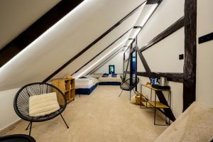 a attic room with two beds and chairs in it at Sowia Ostoja Góry Sowie in Ludwikowice Kłodzkie
