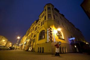 Ein Mann steht nachts vor einem Gebäude in der Unterkunft Hotel Bartis in Bartoszyce