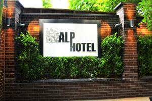 ein Schild für ein Hotel an einer Backsteinmauer in der Unterkunft Alp Hotel in Amsterdam