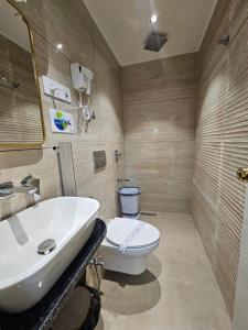 a bathroom with a white toilet and a sink at Hotel Crystal Sarovar in Mirzāpur +16 photos