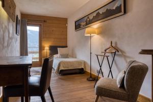 a bedroom with a bed and a desk and chairs at Flocons de Sel - Relais & Chateaux in Megève