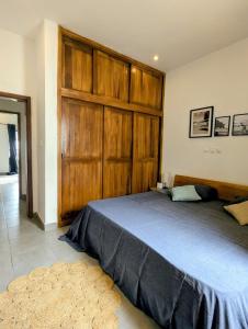 a bedroom with a large bed with a large wooden closet at Villa le Baobab in Bikondo