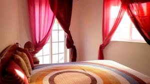 a bedroom with a bed with red curtains and a window at Casa Feliz in Odeceixe