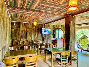 a restaurant with wooden tables and chairs and a television at Sky View Homestay in Tả Van